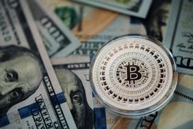 A Bitcoin token and U.S. banknotes.