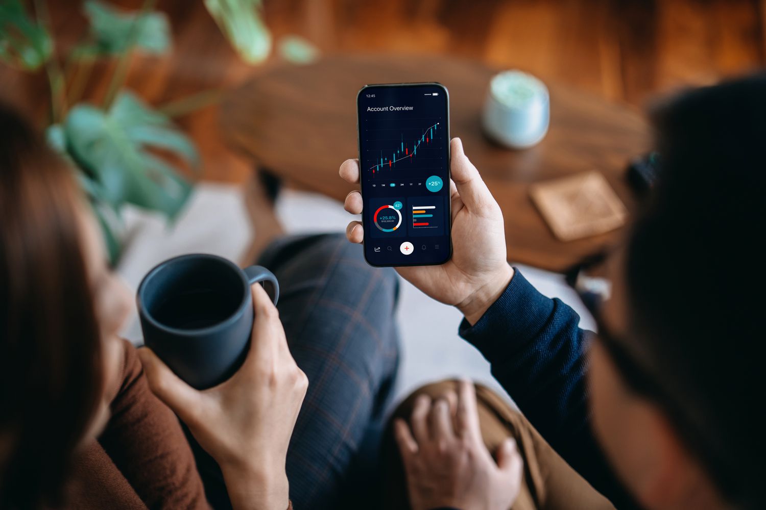 Two people sitting with coffee and looking at options data on a phone
