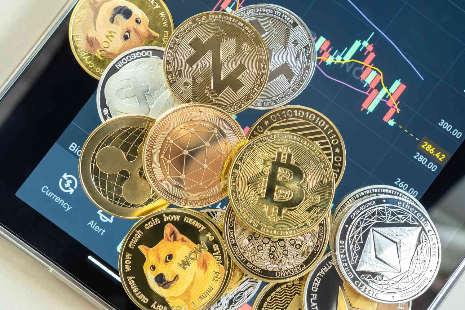 Cryptocurrency coins on top of a tablet showing a trading app