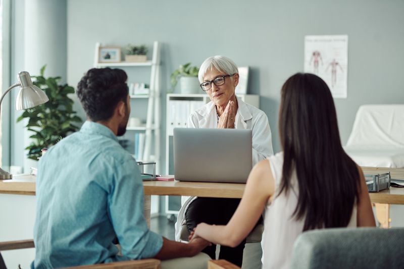 Two people holding hands while sitting in front of a financial advisor 