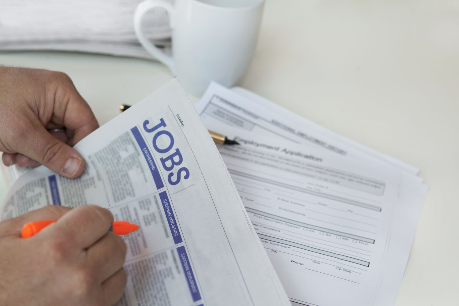 Person highlighting jobs section in a newspaper