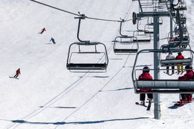 Skiers pass under a chairlift at the Whistler Blackcomb ski resort on Whistler Mountain, British Columbia, Canada