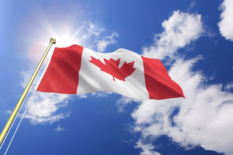 A Canadian flag waving in the wind on a sunny day