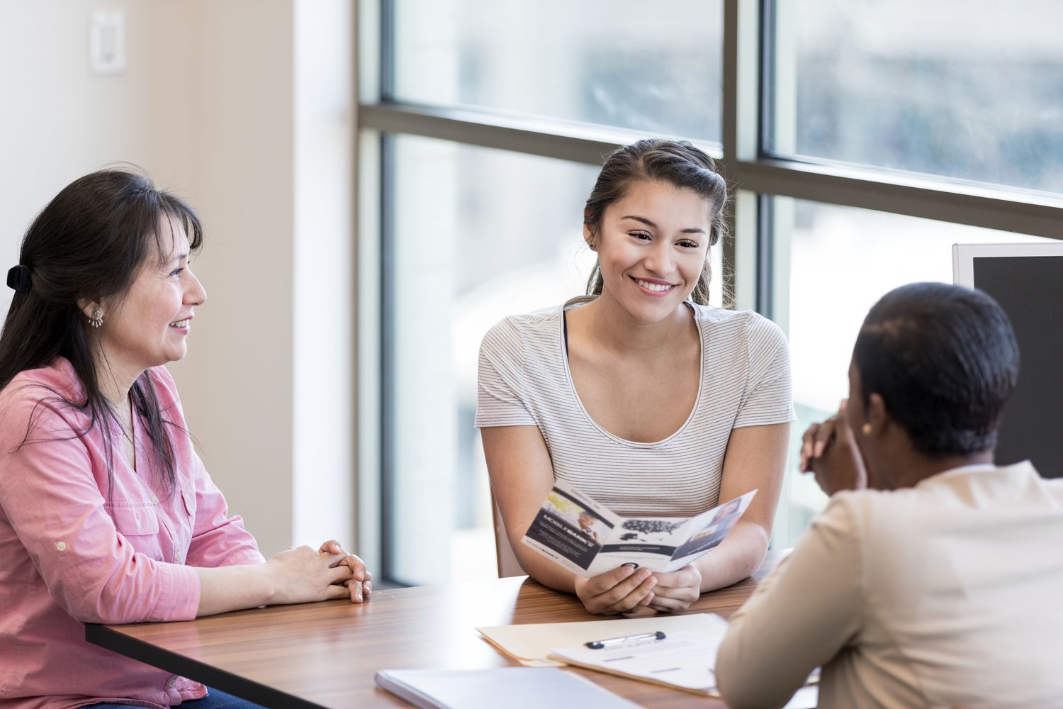Young woman and her mother talk with a female bank employee about a student loan