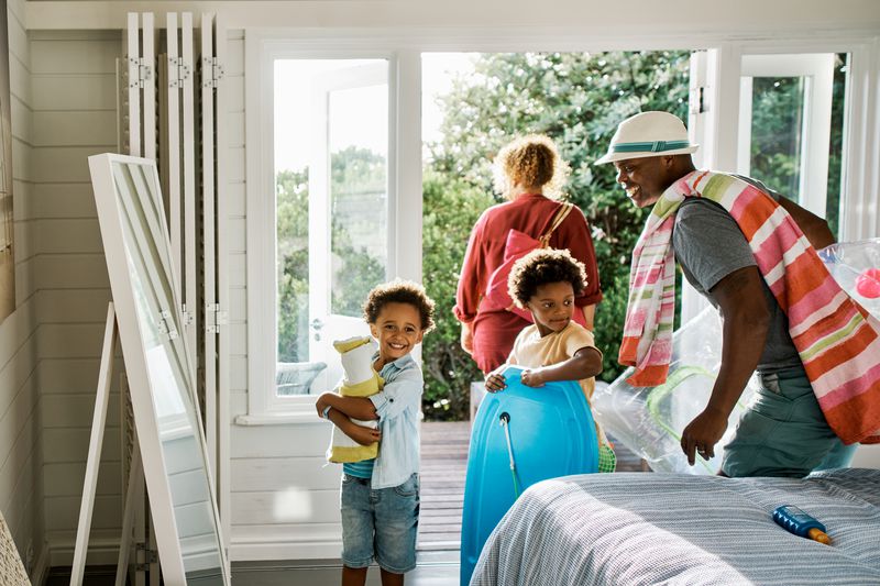 Father, mother and two sons excited to head out on a holiday or vacation getaway. Sibling brothers and their parents with towels and toys for an outing. 
