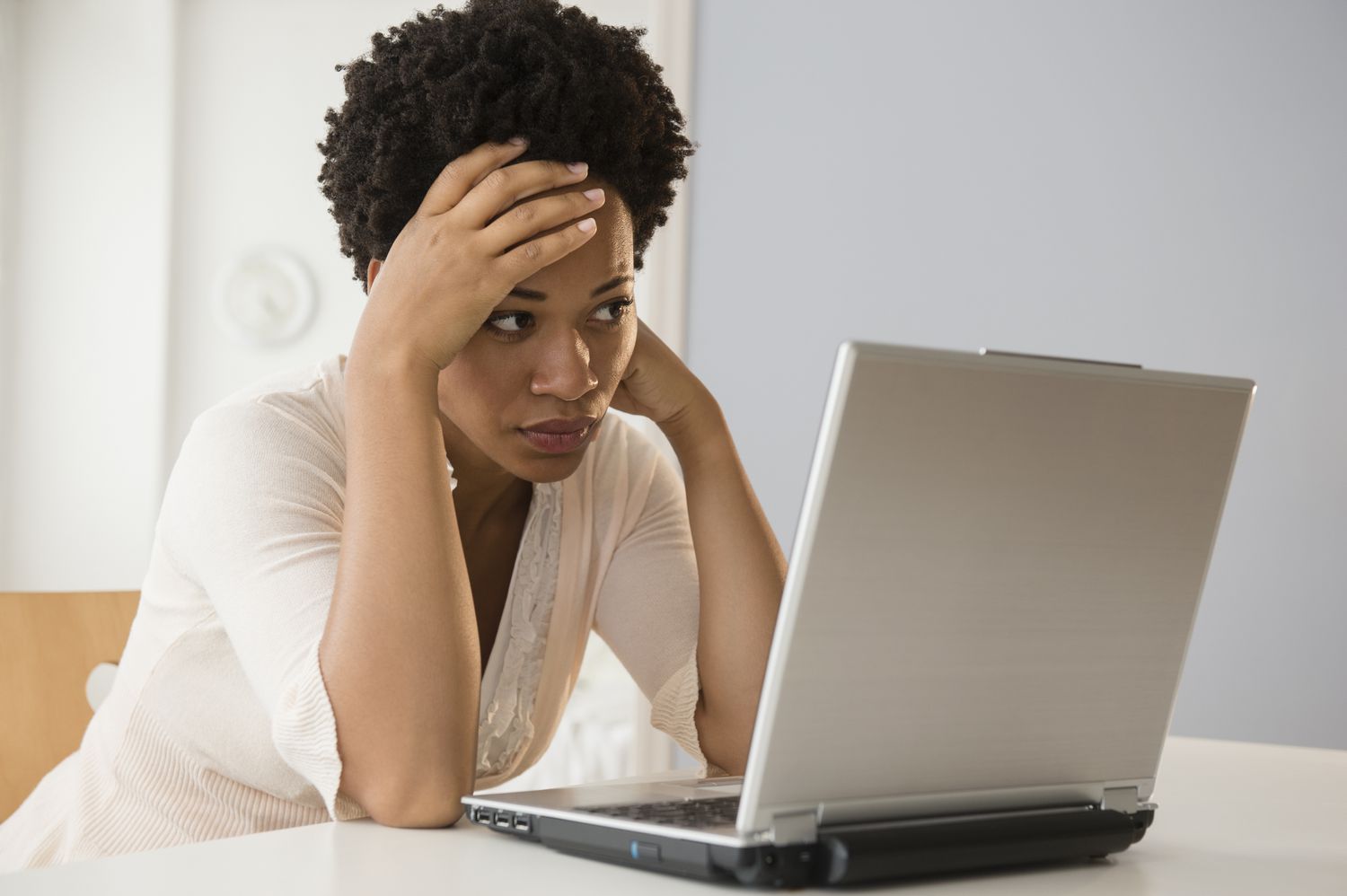 A woman using a laptop, looking frustrated