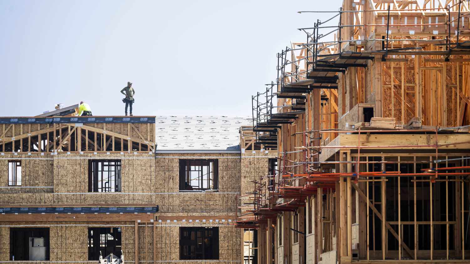 Under construction buildings are seen with people on the roof of a building.