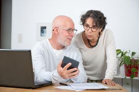 Older couple at home, looking together at mortgage rates and payment calculations