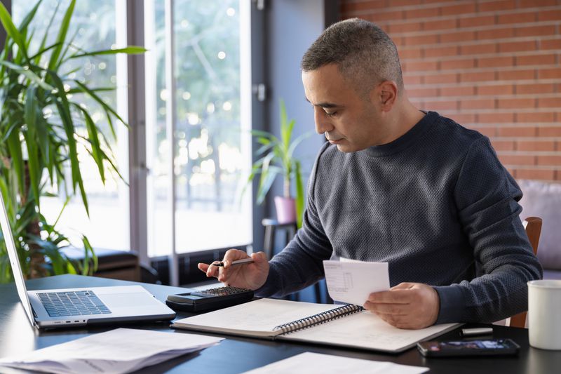 A man reviewing papers with a calculator