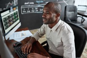 A stock trader reviews financial data on several computer monitors.