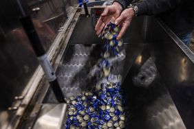 Port City Brewing Company Founder and President Bill Butcher adds bottle caps, which he imports from Mexico, into the bottle machine at his brewery in Alexandria, Virginia, on March 13, 2025. For US craft brewer Bill Butcher, President Donald Trump's expanding range of tariffs have sparked an unexpected impact -- a shortage of bottles to package his beer -- while uncertainty looms over his business costs