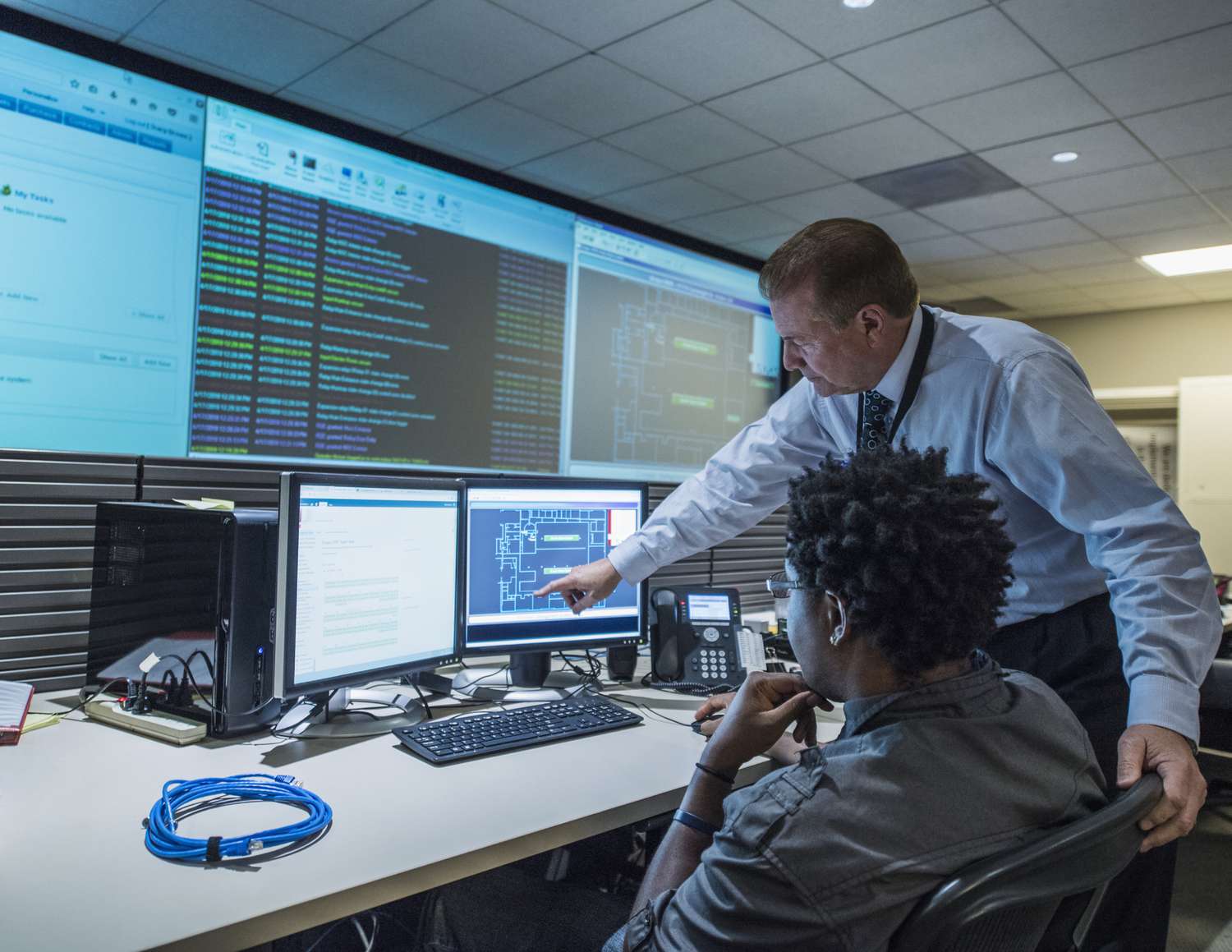 Colleagues work on cybersecurity issues in a control room.