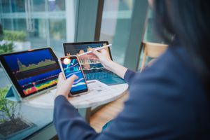 Person analyzing stock charts on multiple devices at a desk