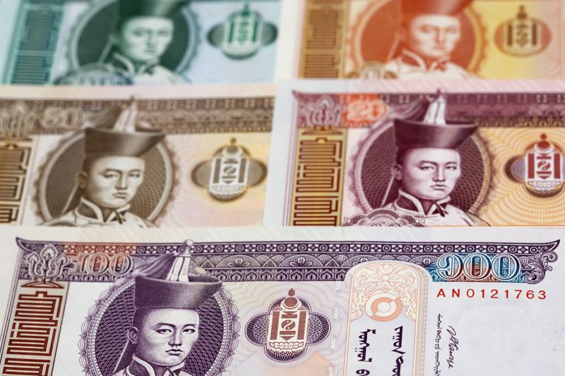 A close up of a collection of Mongolian Tugrik banknotes featuring a past ruler spead on a surface.