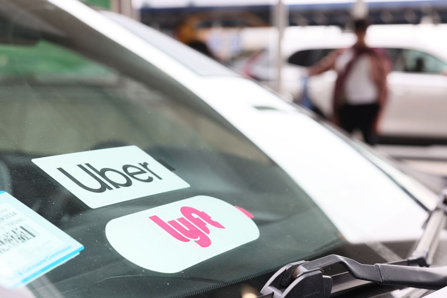 Uber and Lyft company decals on a car window. 