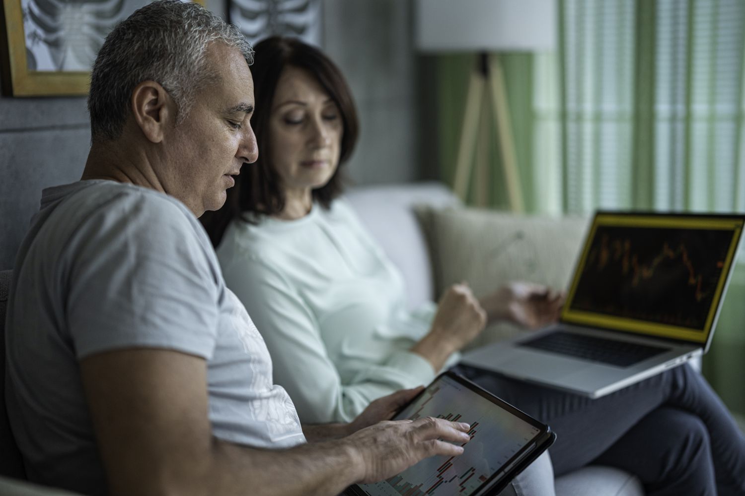 A couple sitting next to each other on a laptop, studying charts.