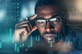 A person with glasses looking in at a screen of financial prices.