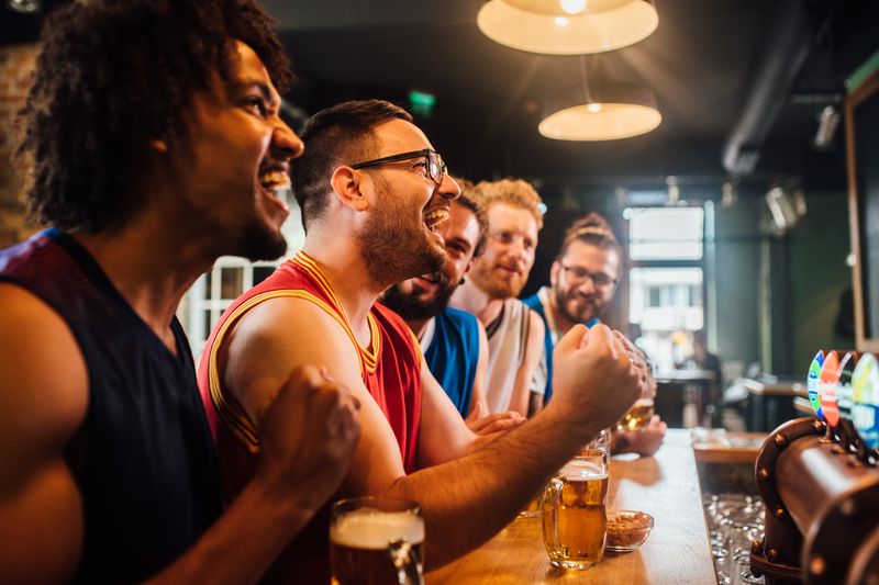 Young men with beers cheering at a bar