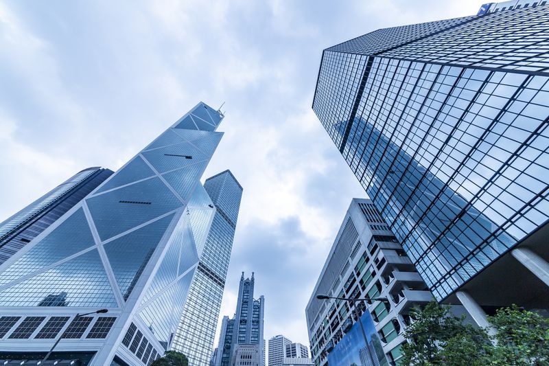 Bottom view of modern skyscrapers in business district against blue sky