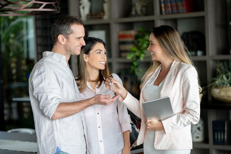 a couple receiving a key from a person holding a tablet