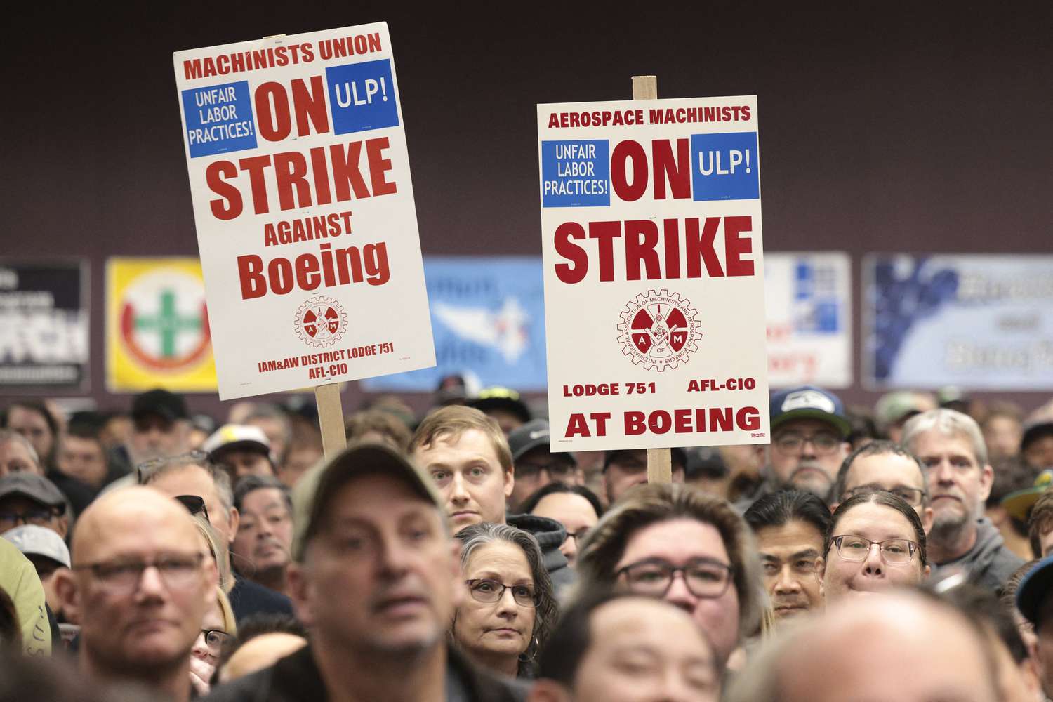 A group of people hold signs that say "Aerospace machinists on strike at Boeing" during a rally.
