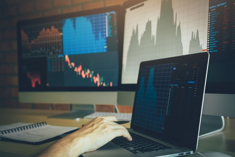A cropped hand of businessman using laptop on desk in office.