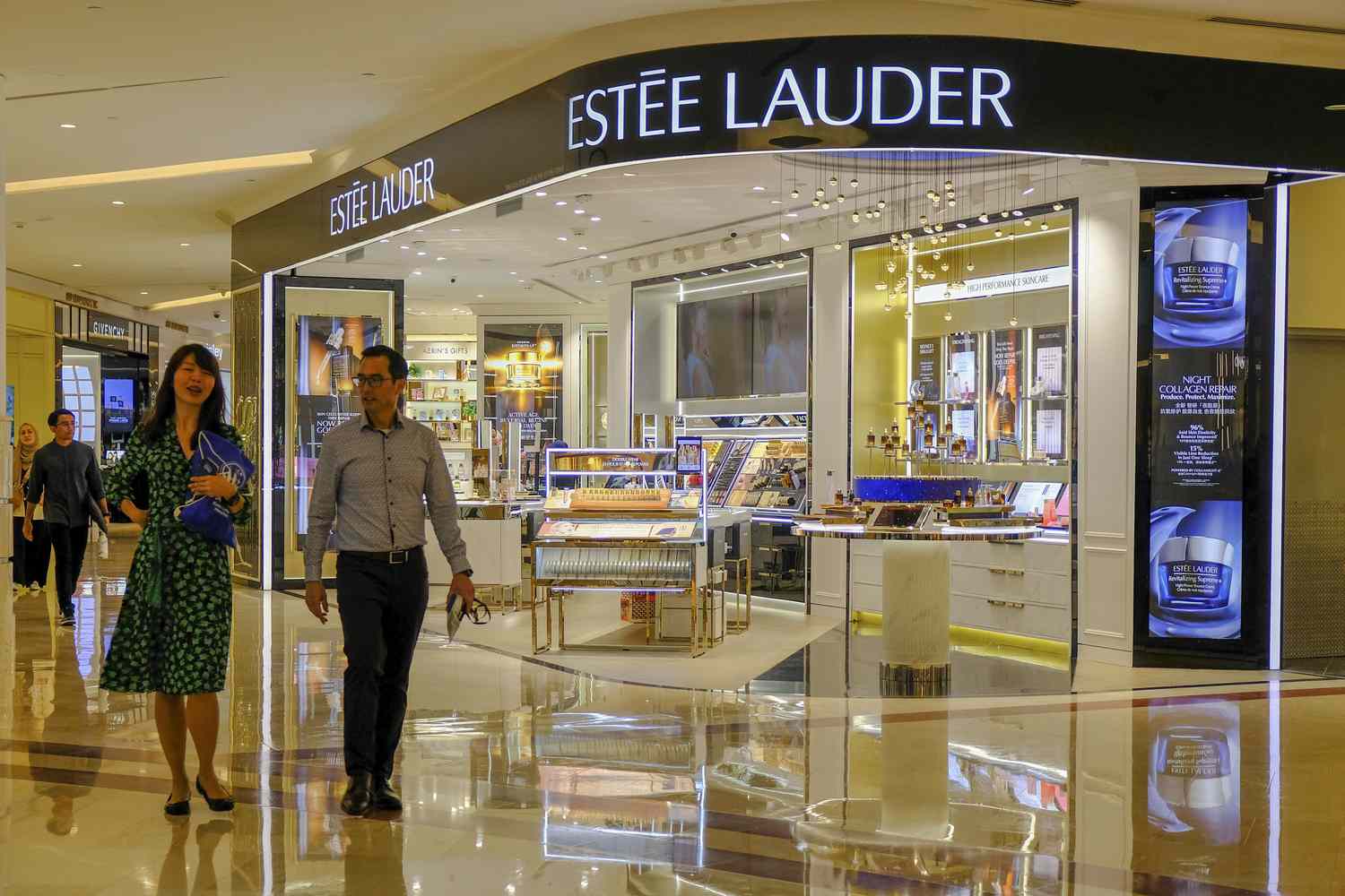 A couple walks by an Estee Lauder store in Kuala Lumpur.