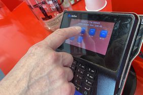 Person selecting a tip while using touch screen credit card payment at Five Guys restaurant, Queens, New York