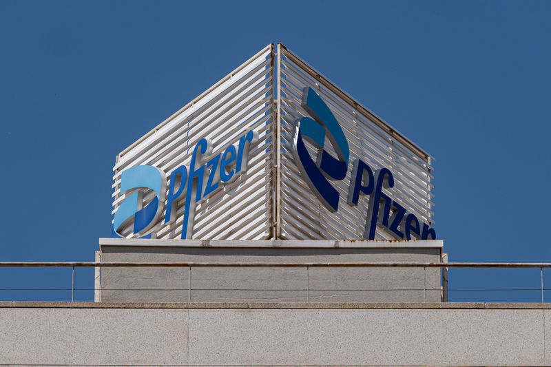 The blue Pfizer logo is seen on a sign above a gray building.