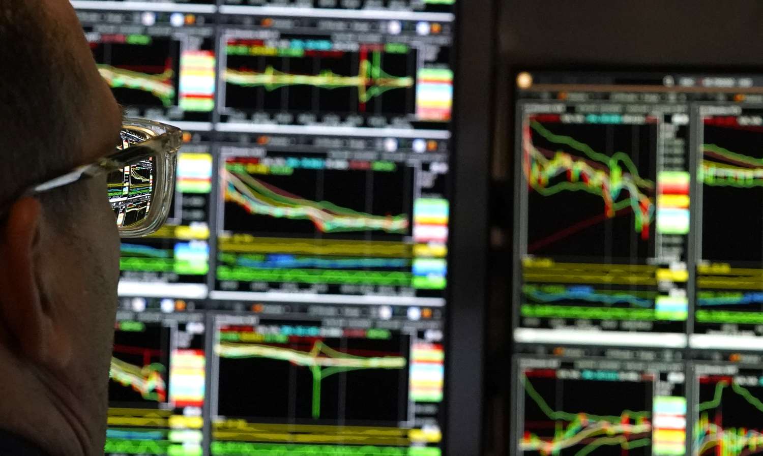 A trader looking screens with stock price charts at the New York Stock Exchange.
