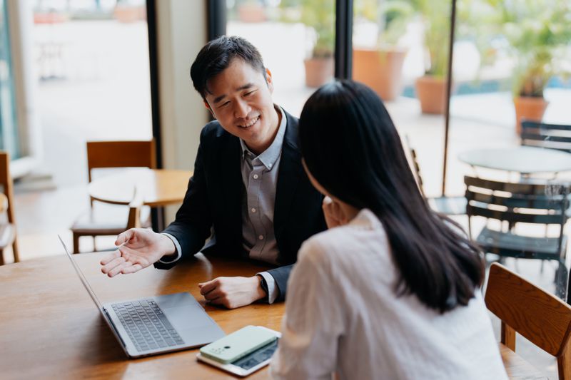 insurance agent has discussion with client in cafe
