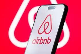 The logo of Airbnb, Inc. is displayed on a smartphone screen, with the company's branding visible in the background