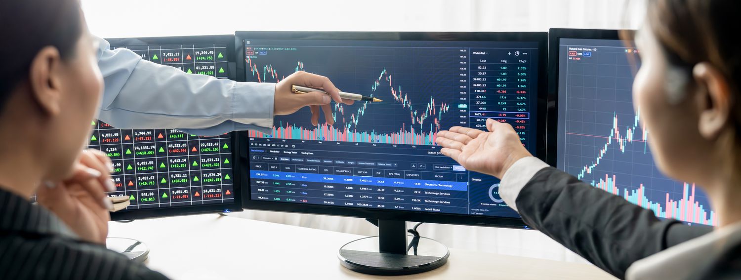 Managers of a synthetic exchange traded fund discuss differing views of the financial data shown on a set of monitors.