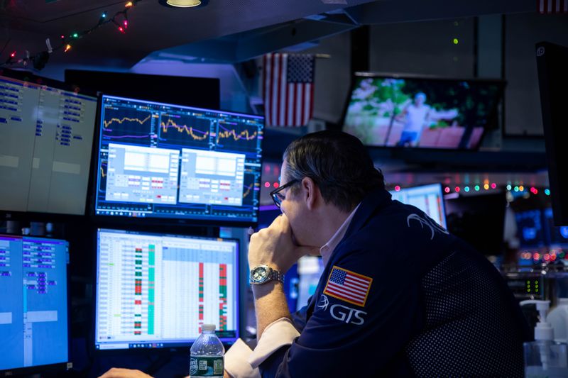 A trader on the floor of the NYSE reviewing data and charts on multiple monitors