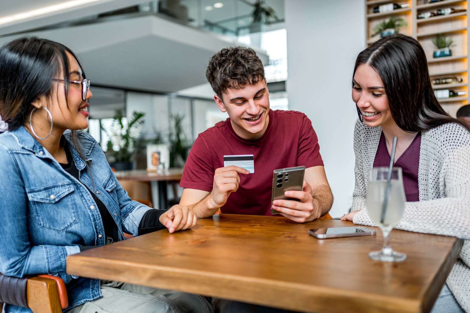 Friends sitting around for a drink while talking about a credit card with good APR.