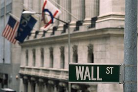 Close up of Wall St sign in New York City with stone building in background