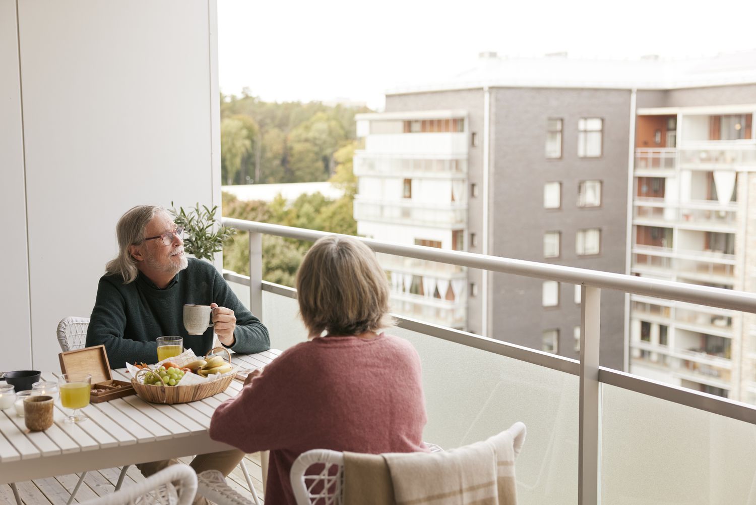An older couple sitting on the balcony of their landominium. 