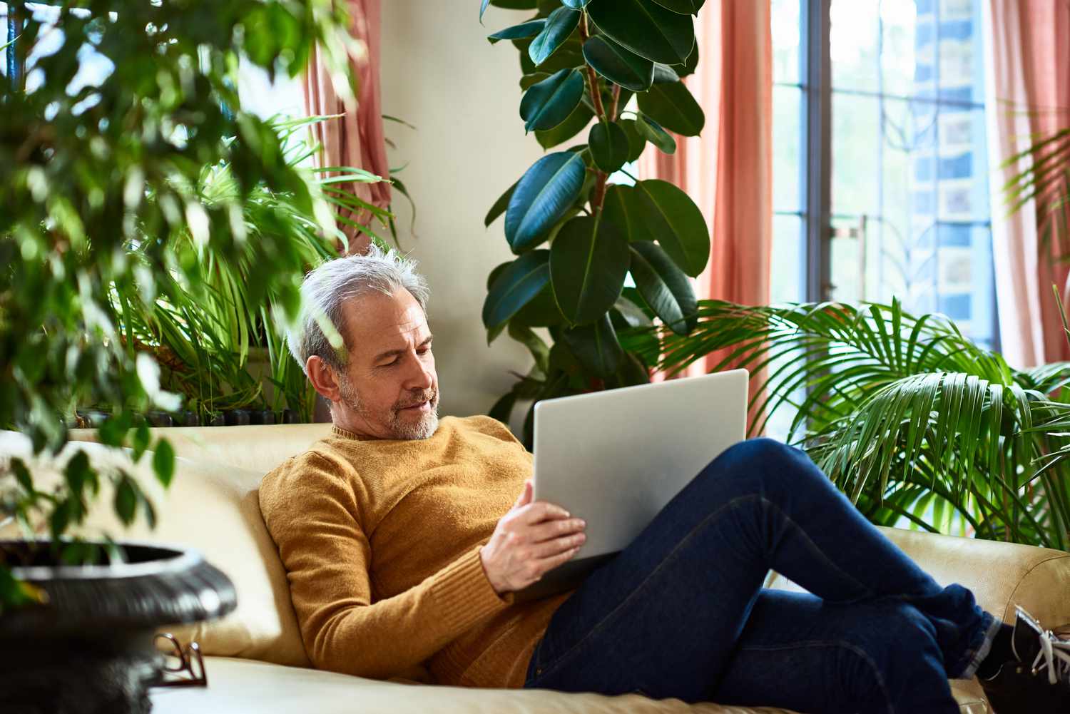 Mature man sitting on sofa using laptop