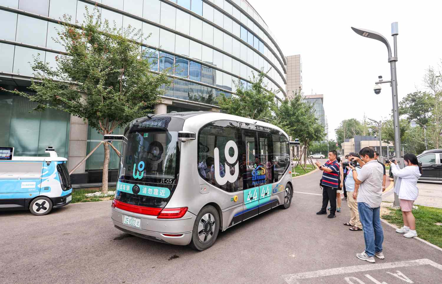 People take photos of WeRide Robobus, a fully-driverless shuttle capable of SAE Level 4 autonomous driving, at Beijing High-level Autonomous Driving Demonstration Area on July 11, 2024 in Beijing, China