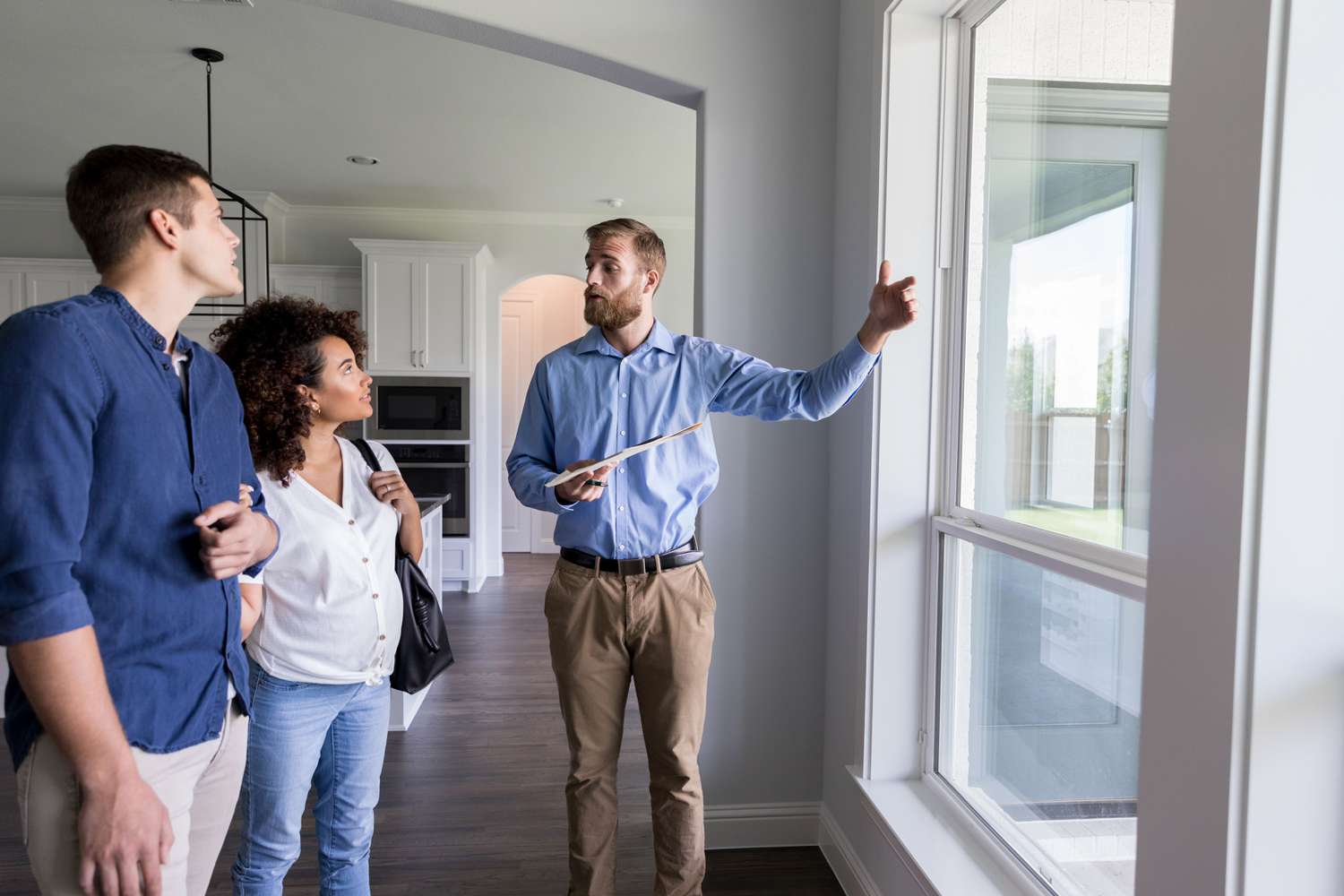 Millennial couple looking at a house for sale with a real estate agent