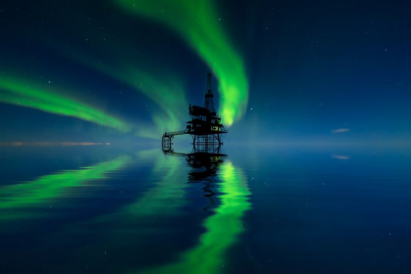 Oil platform at sea at the northern lights background. Oil production in the north - stock photo