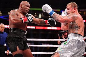 Mike Tyson and Jake Paul throw punches during a boxing match.