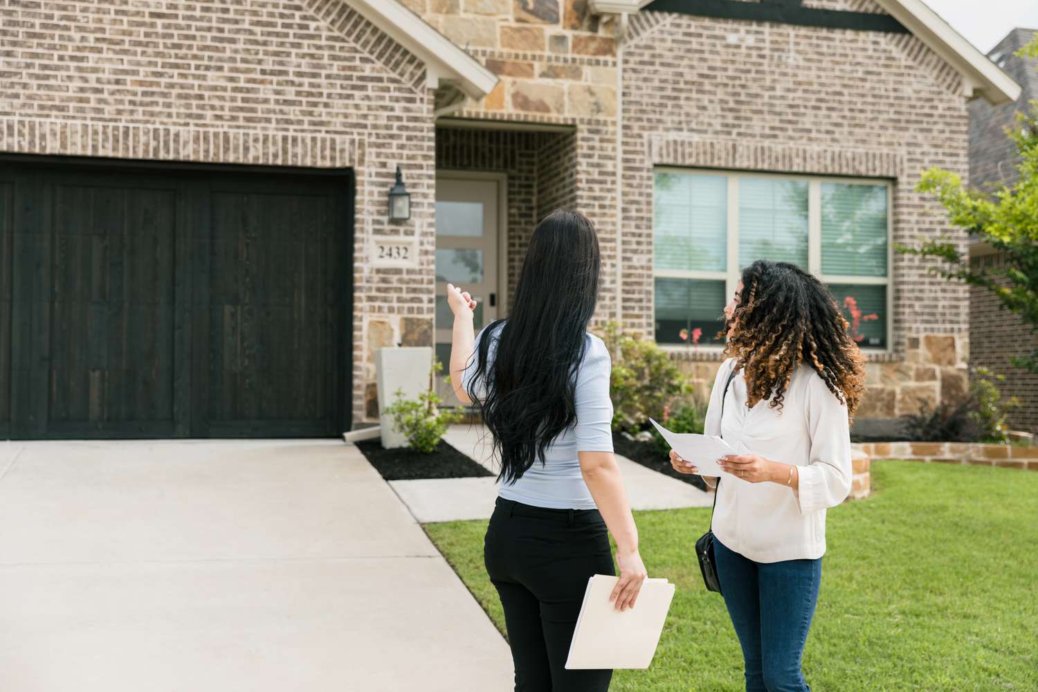 A woman speaks with a real estate agent outside a house