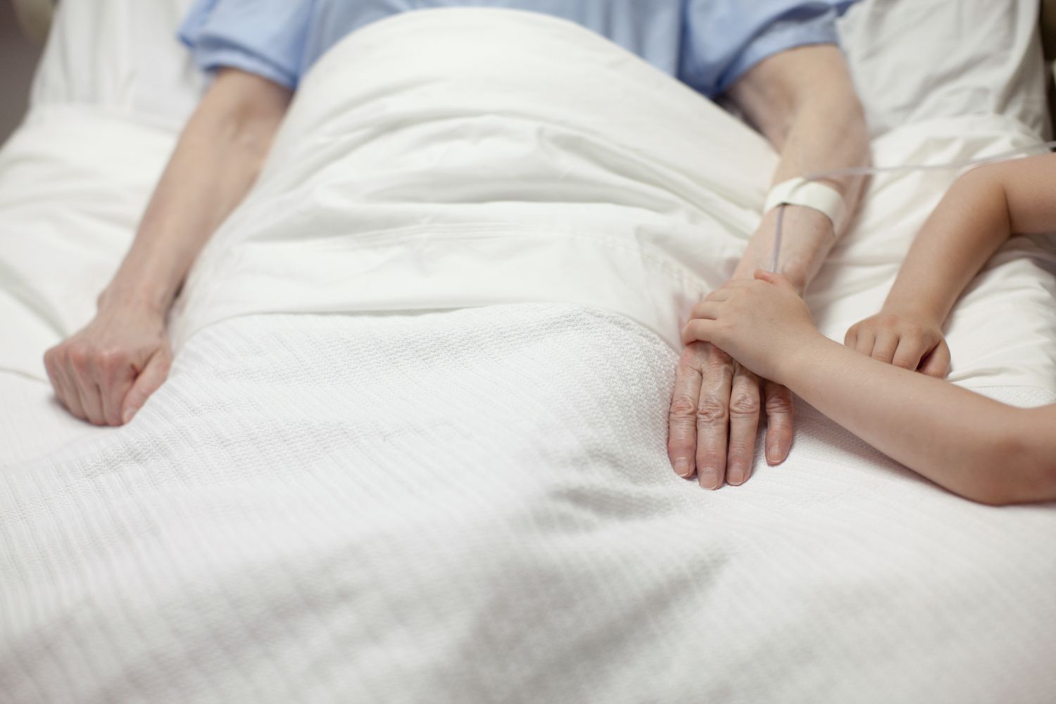 Young girl holding grandma's hand in hospital short term disability