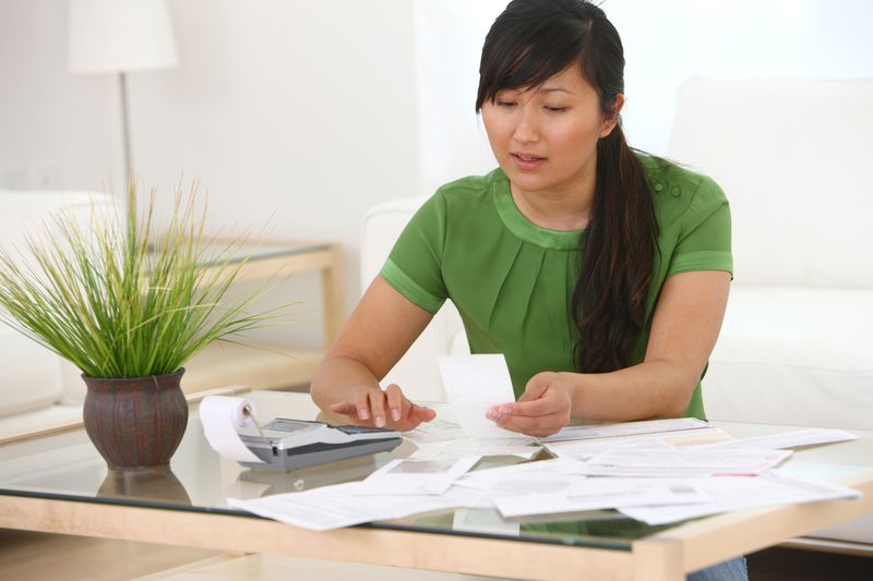 Photo shows woman with a desk full of paperwork to indicate that refinancing a mortgage is complex.