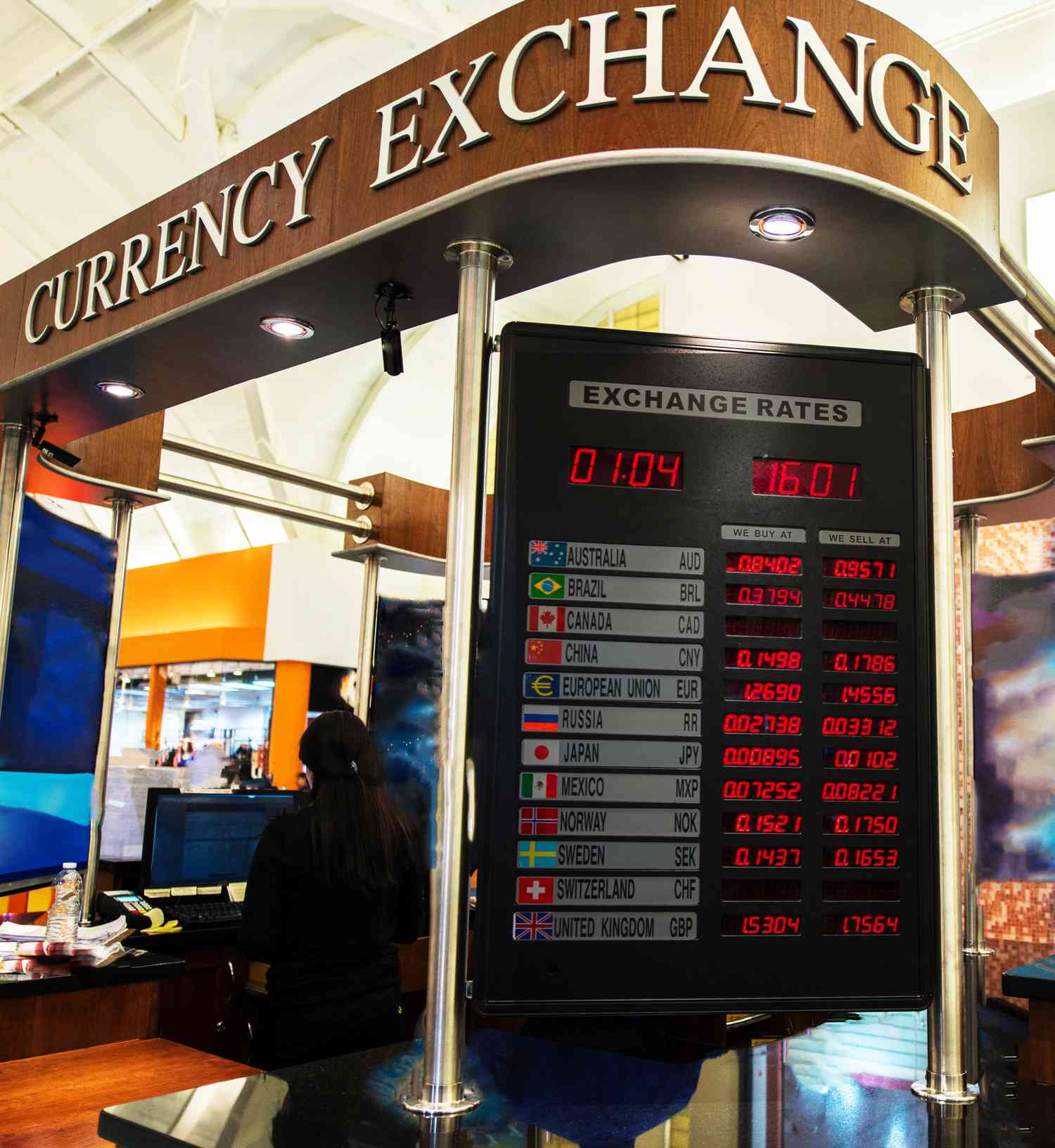 A currency exchange booth at an airport displays the current spot exchange rate for various currencies.