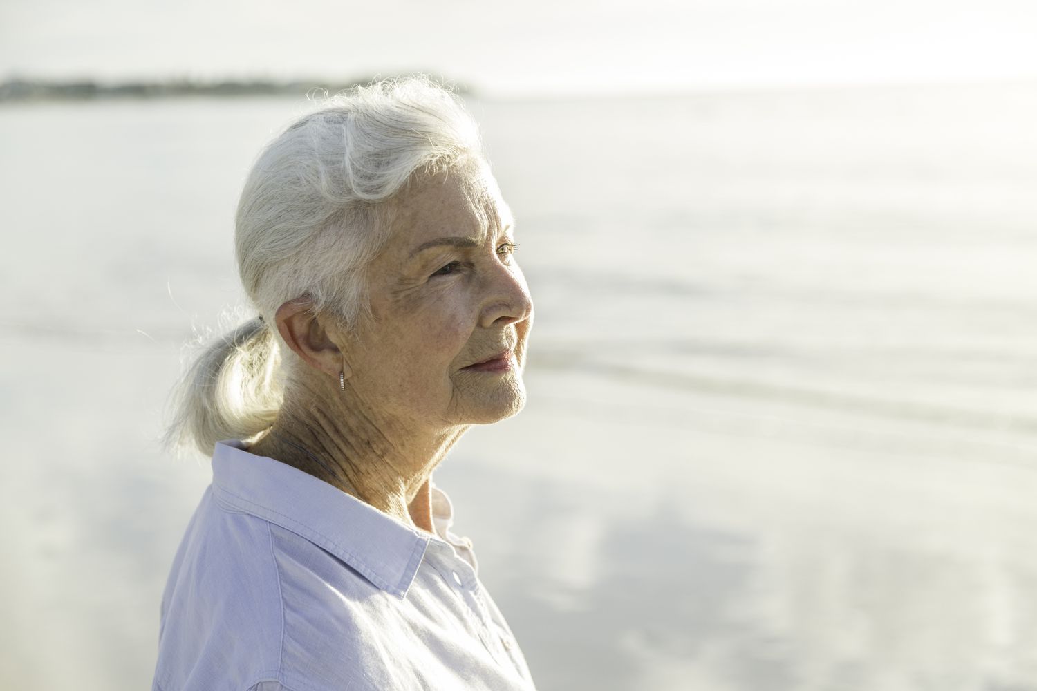 Woman on a beach looks into the distance. 