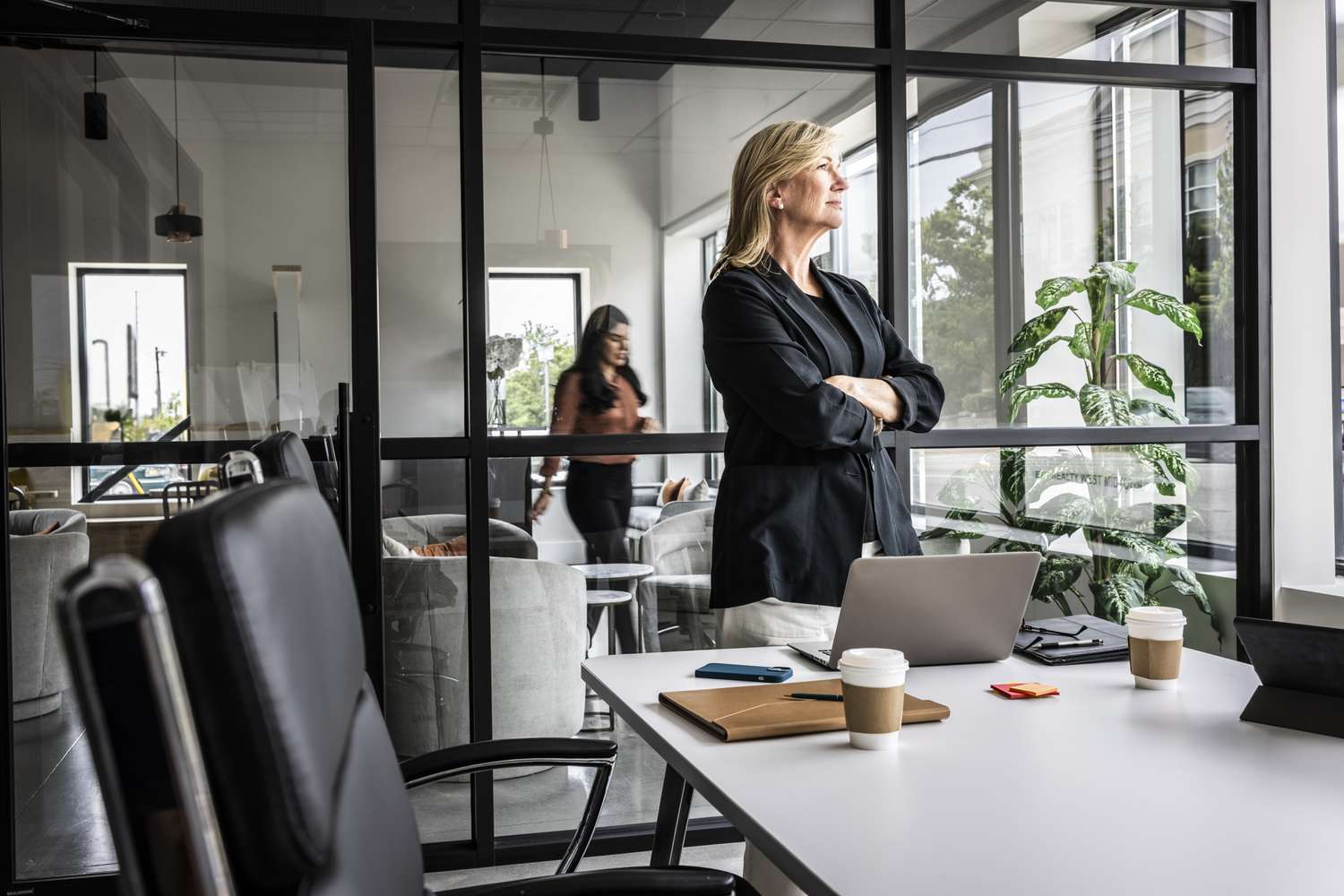 Satisfied looking business woman standing in a conference room and looking out the window.