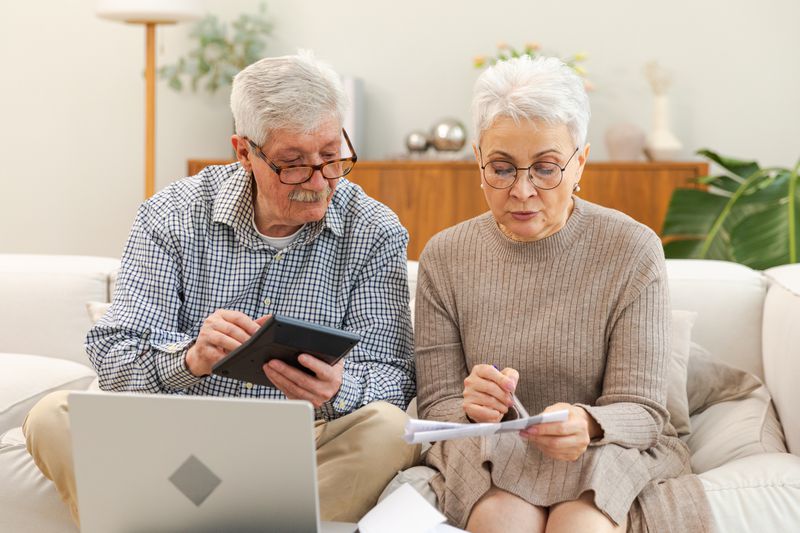 Older couple sitting on their sofa and making mortgage calculations
