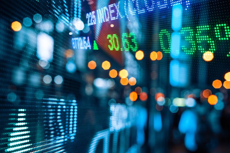 Display of stock market quotes with city scene reflection at night